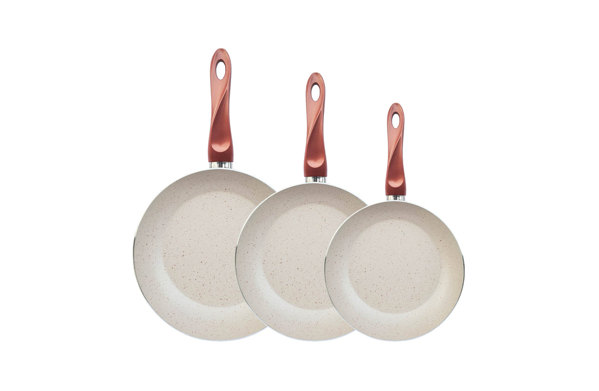 Three Papilla everyday frying pans with speckled cream interiors and copper-red handles